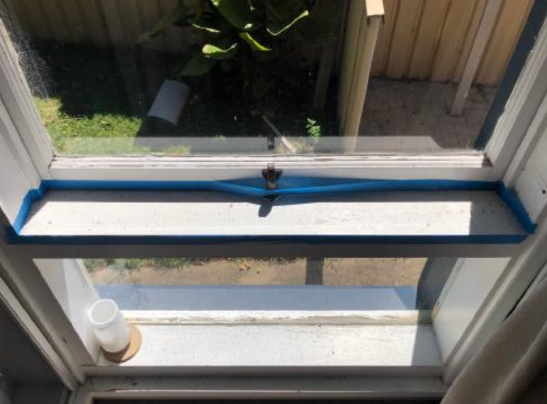 Blue painter's tape peeling off a white window ledge.